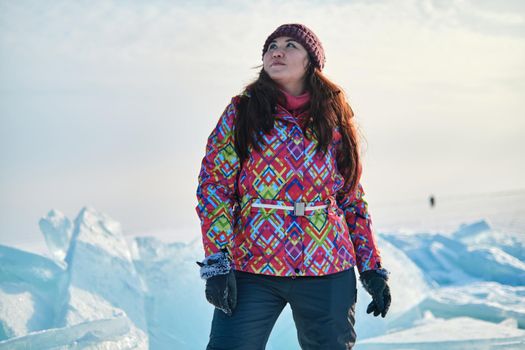 A woman in a ski suit climbs on blocks of ice, fun, fun, rest, winter