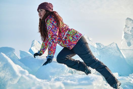 A woman in a ski suit climbs on blocks of ice, fun, fun, rest, winter