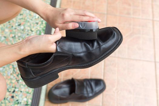 Hands polish leather black shoes.