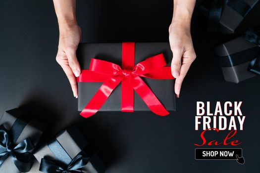 black friday sale, woman hand give the gift box on black background