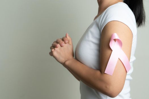 pink badge ribbon on praying woman arm to support breast cancer cause. breast cancer awareness concept