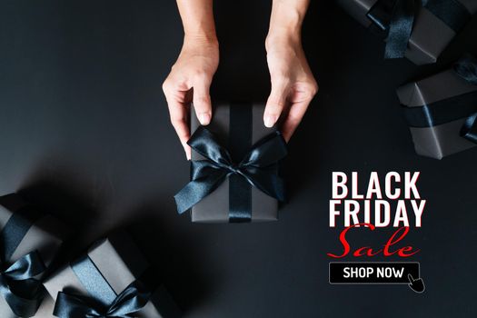 black friday sale, woman hand give the gift box on black background
