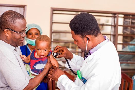 a young man catches his baby during the doctor examines him at the hospital.a young man catches his baby during the doctor examines him at the hospital.