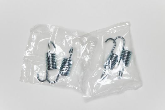 Repair kit for brakes, metal springs in the package. Set of spare parts for car brake repair. Details on white background, copy space available. UHD 4K.