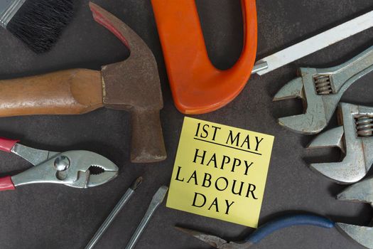 Labour day text on yellow notepad with repair equipment and many handy tools on a dark background