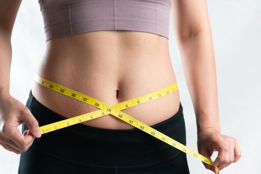 young woman measuring her belly waist with measure tape, woman diet lifestyle concept