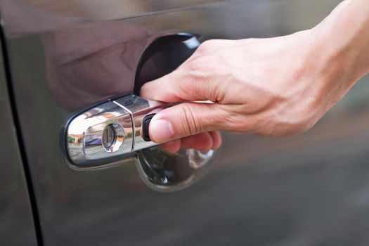 Hand press unlock button alarm system on black car .