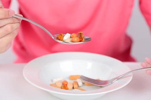 Young women eating medicine capsules on spoon for health.