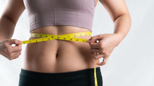 young woman measuring her belly waist with measure tape, woman diet lifestyle concept