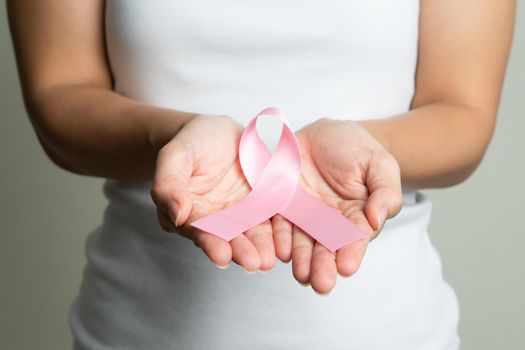 Woman hand holding pink ribbon breast cancer awareness.