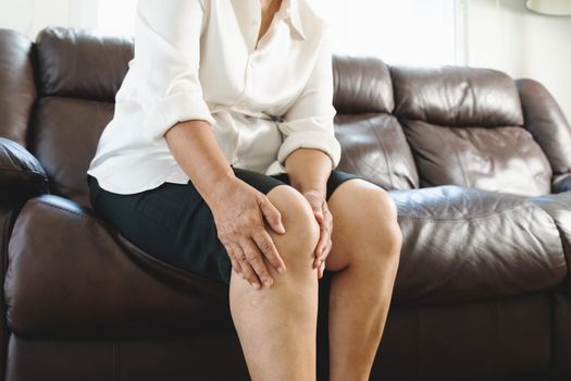 senior woman suffering from knee pain at home, health problem concept