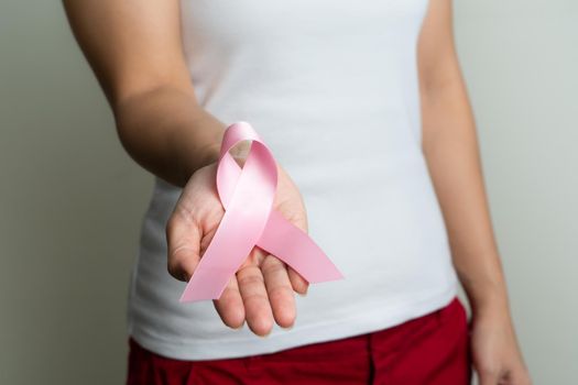 Woman hand holding pink ribbon breast cancer awareness.