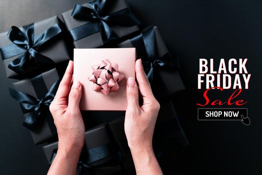 black friday sale, woman hand give the gift box on black background