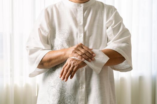 Senior woman cleaning her hands with white soft tissue paper. isolated on a white backgrounds