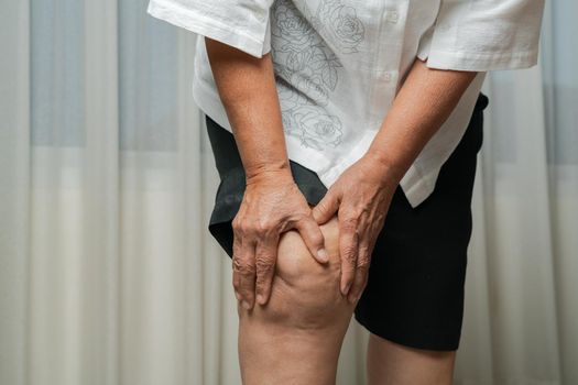 senior woman suffering from knee pain at home, health problem concept