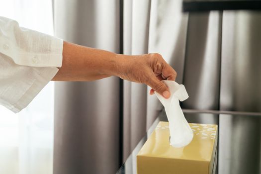 Senior women hand picking napkin/tissue paper from the tissue box