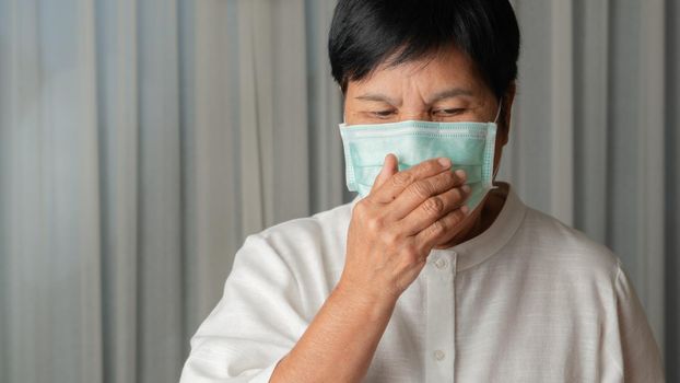 asian old woman wearing a face mask indoor coughing