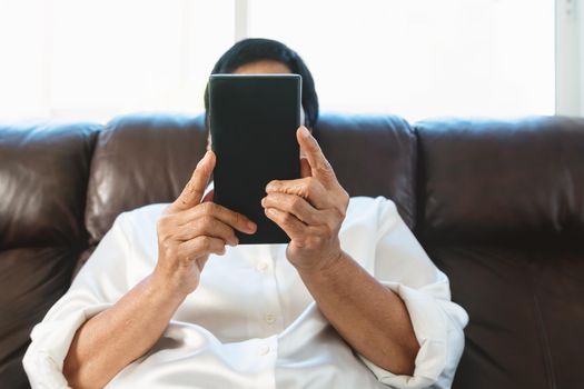 senior woman using mobile phone while sitting on sofa at home