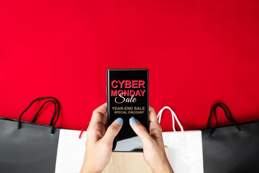 Cyber Monday Sale Clearance Discount Concept, woman hand holding smartphone with shopping bag.