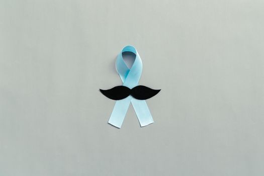 November light blue ribbon with mustache on gray background with copy space, Prostate cancer awareness month, men's health concept