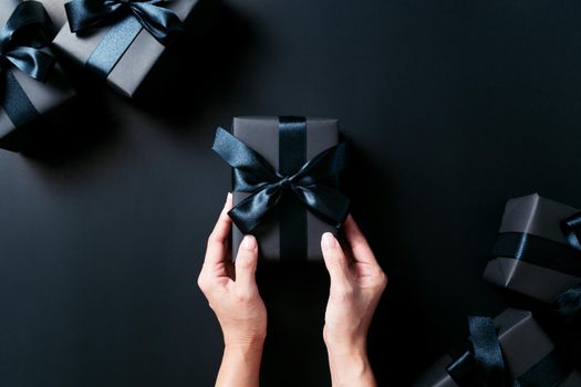 Boxing day Sale concept, woman hand give the gift box on black background