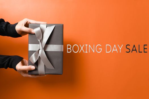 Boxing Day sale, young woman hand with a gift box offer to receiver