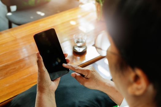 senior lady sitting in a chair and touching the screen of smartphone, online shopping concept