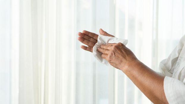 Senior woman cleaning her hands with white soft tissue paper. isolated on a white backgrounds