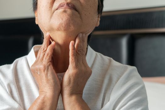 Senior adult women touching the neck feeling unwell coughing with sore throat pain.Healthcare and medicine concept