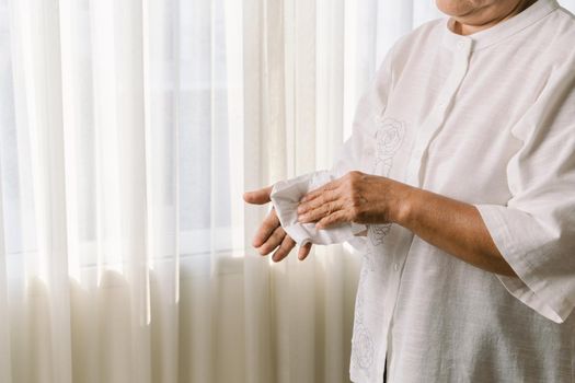 Senior woman cleaning her hands with white soft tissue paper. isolated on a white backgrounds