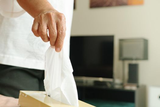 Senior women hand picking napkin/tissue paper from the tissue box