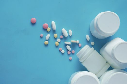 white color medical pills spilling on blue background ,
