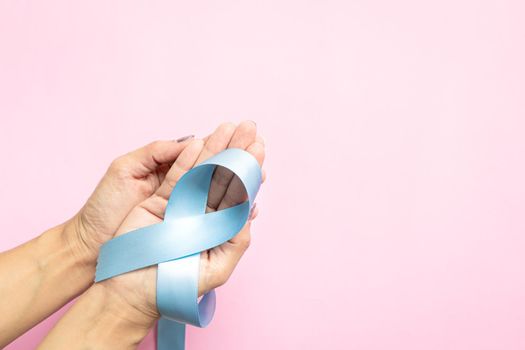 November light blue ribbon on woman hand with copy space, Prostate cancer awareness month, men's health concept