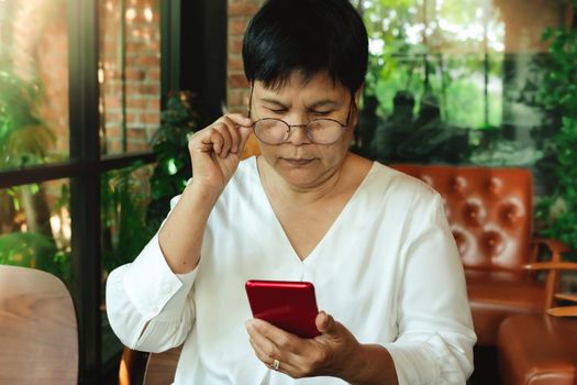 Senior woman wearing  glasses and lookning at smartphone