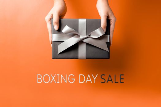 Boxing Day sale, young woman hand with a gift box offer to receiver