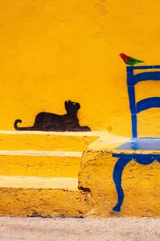 Famous Illustration on Linosa's wall of a cat looking at a bird sitting on a chair, Pelagie island. Sicily