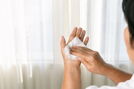 Senior woman cleaning her hands with white soft tissue paper. isolated on a white backgrounds