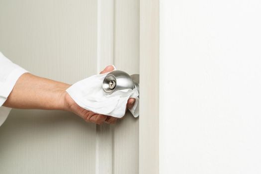 Cleaning door knob with alcohol spray for Covid-19 Coronavirus prevention