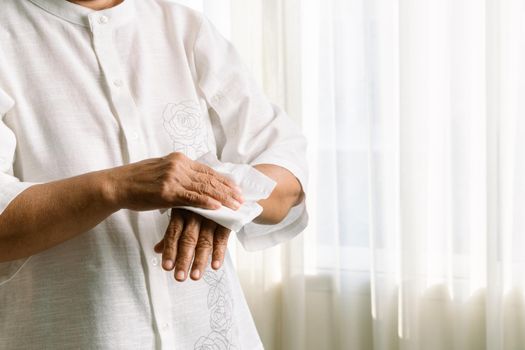 Senior woman cleaning her hands with white soft tissue paper. isolated on a white backgrounds