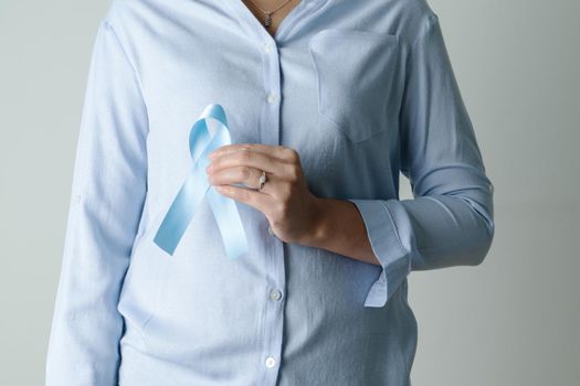 November light blue ribbon on woman hand with copy space, Prostate cancer awareness month, men's health concept