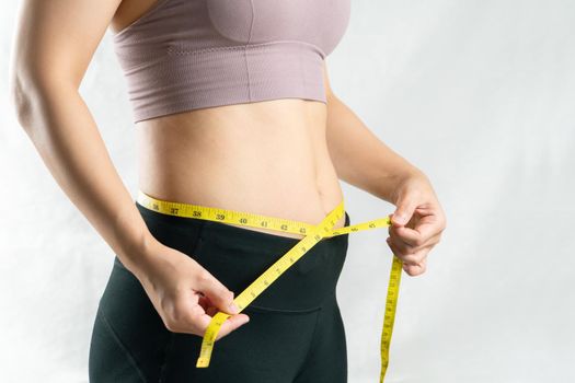 young woman measuring her belly waist with measure tape, woman diet lifestyle concept