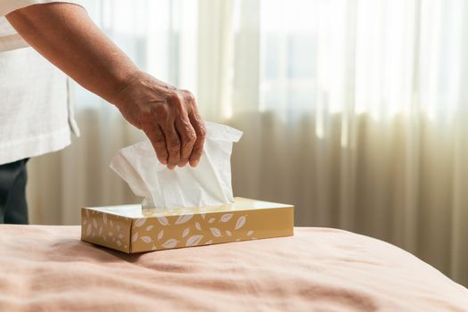 Senior women hand picking napkin/tissue paper from the tissue box