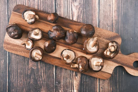 raw champignon mushroom on a chopping board on table .