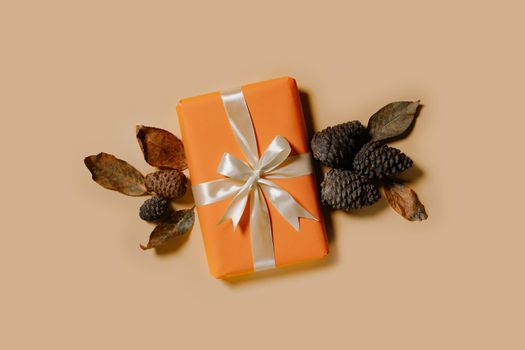 Giftbox, autumn leaves and pine cones on pastel colored background. Top view. Happy Thanksgiving Day