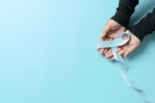 November light blue ribbon on woman hand with copy space, Prostate cancer awareness month, men's health concept