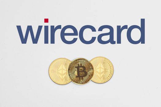 Tashkent, Uzbekistan - April 2, 2021: Bitcoin and Ethereum cryptocurrency coins on Wirecard logo. Symbol of bitcoin rolling out of cryptocurrency