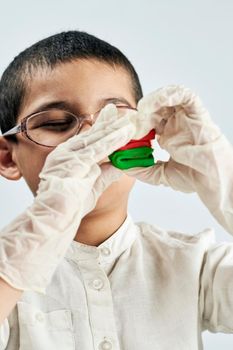 A portrait of cute boy in protective gloves and glasses making plasticine figures on the table