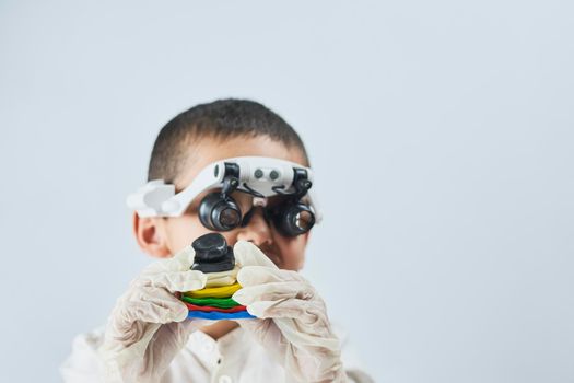 A boy in head magnifying glasses headset learning Incredible chemistry of plastiline. Tactile play or sensory play for older kids
