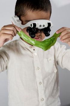 A small boy wearing special magnifying glasses and busy with interesting scientific experiments on slime at the workshop