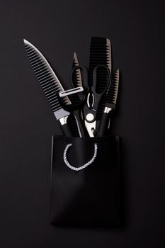 Black Friday concept. A kitchen set of black knifes on black background. Sharp knifes, kitchen slicer and scissors in the shopping bag packaged and bowed with ribbon
